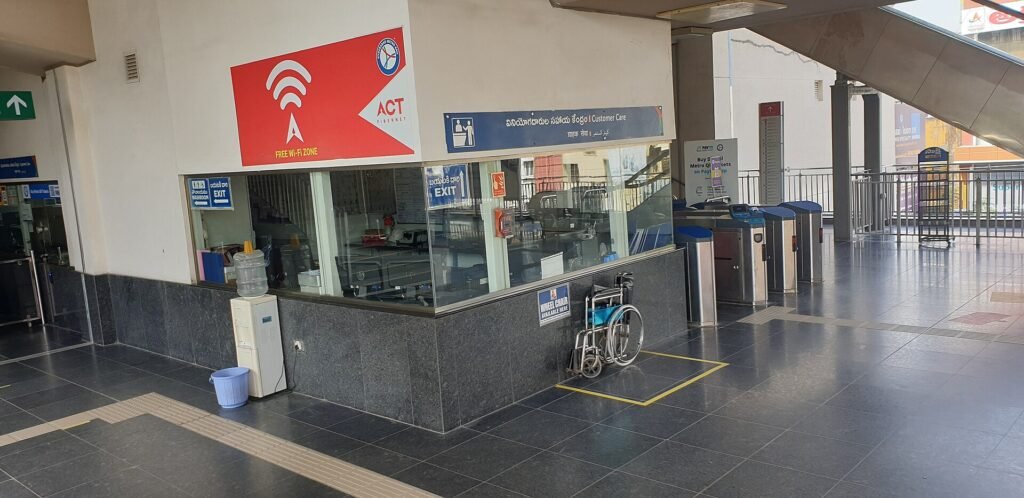 A glass-fronted customer service centre kiosk beside the ticket gates at a Hyderabad Metro station in India