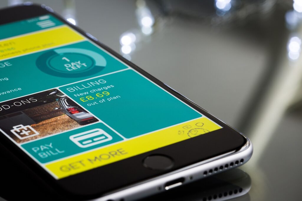 A hand holding a smartphone showing a mobile banking app menu