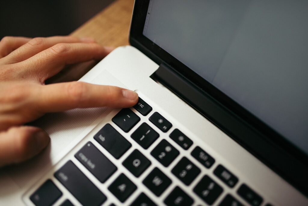 A hand pressing a key on a laptop keyboard in a minimal workspace