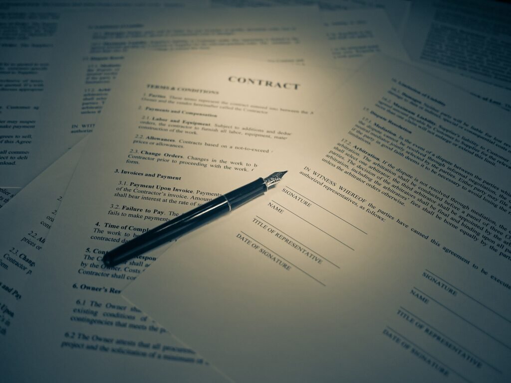 A hand signing a printed legal contract with a pen