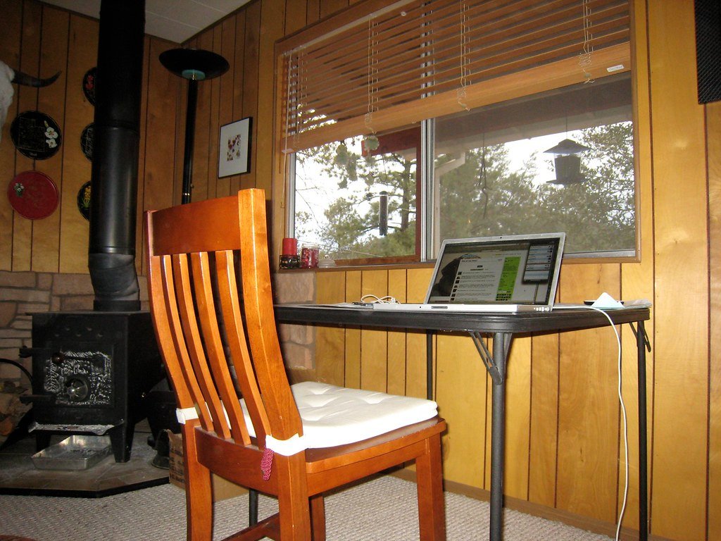 A home office desk with a computer set up beside a window