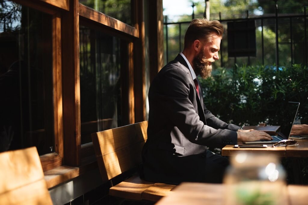 A man in a suit working on a laptop at an outdoor cafe table
