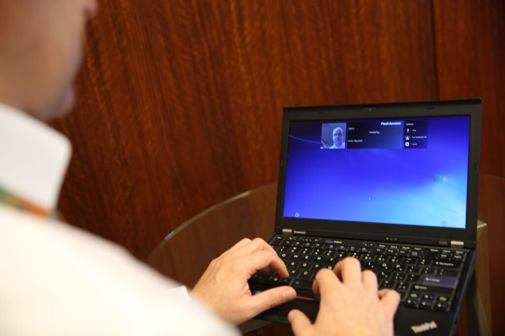 A person logging in to a laptop using the built-in camera for facial recognition