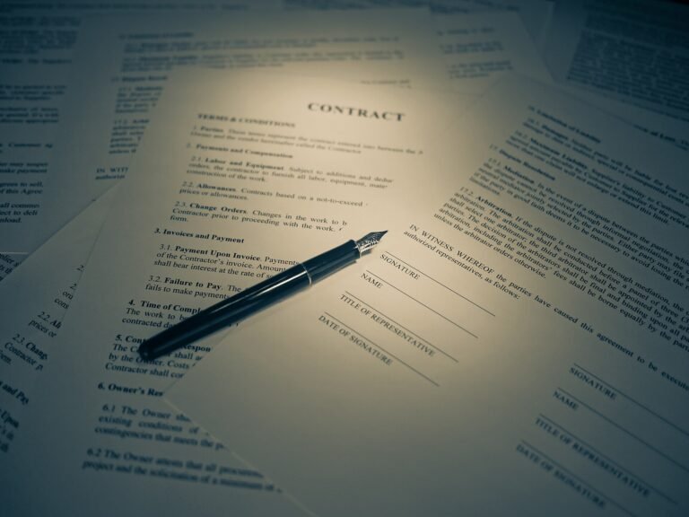A printed contract with signature lines and a fountain pen resting on top