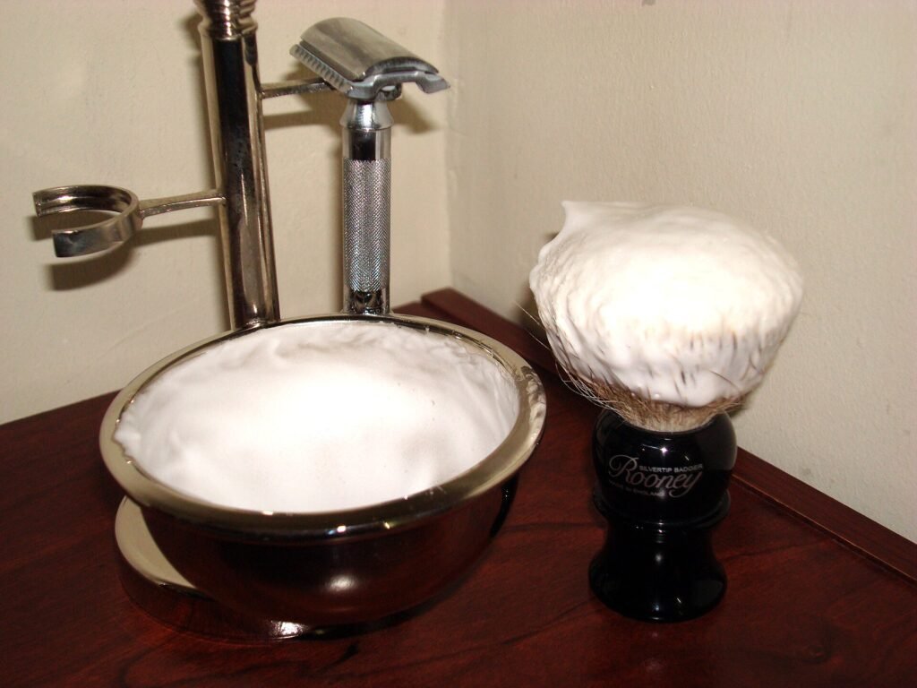 A shaving brush, razor and shaving cream laid out on a bathroom counter