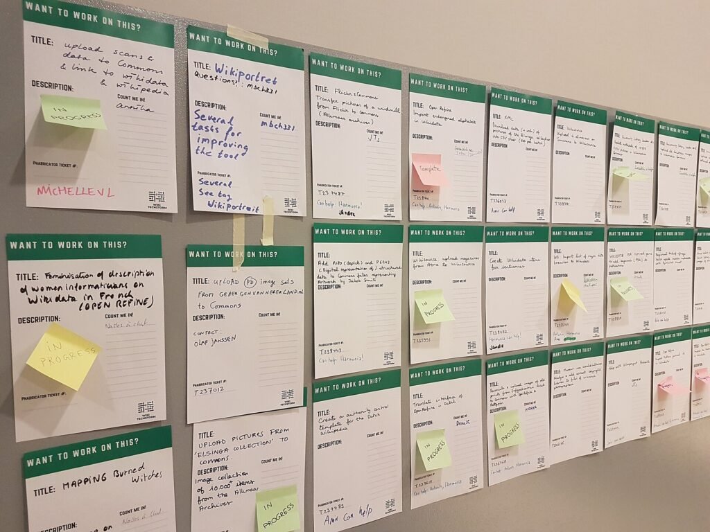 A wall covered with task cards and small sticky notes tracking project work