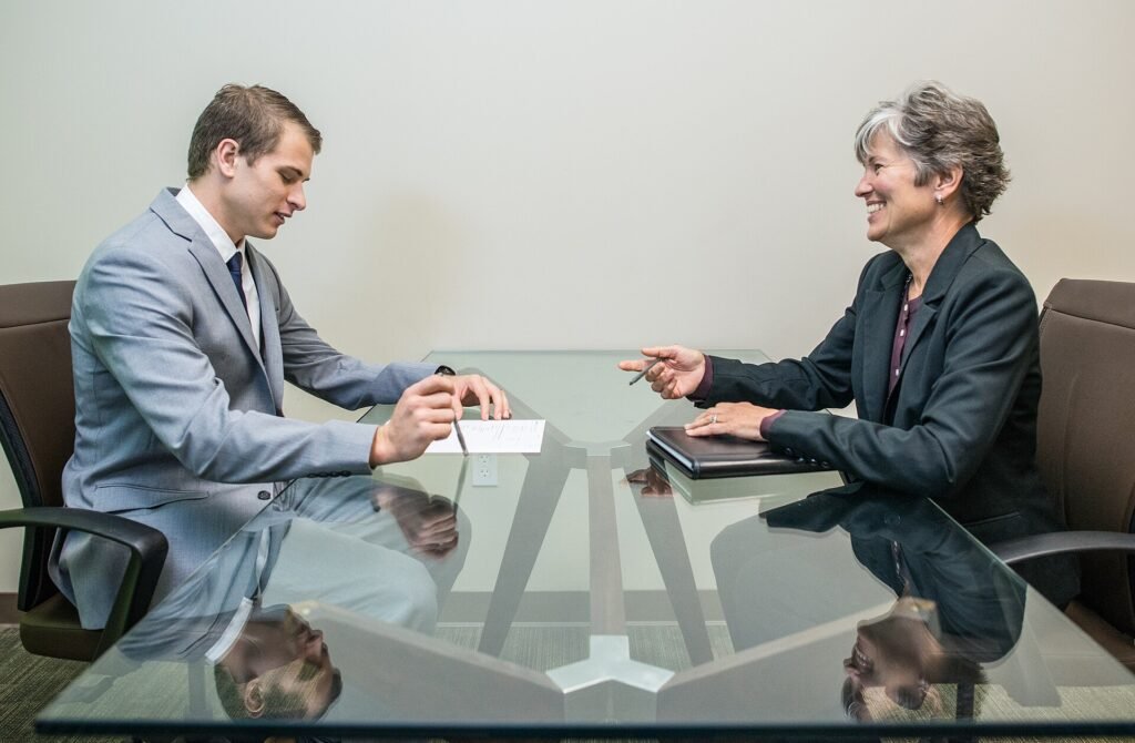 A young man in a shirt and tie answers questions during a job interview