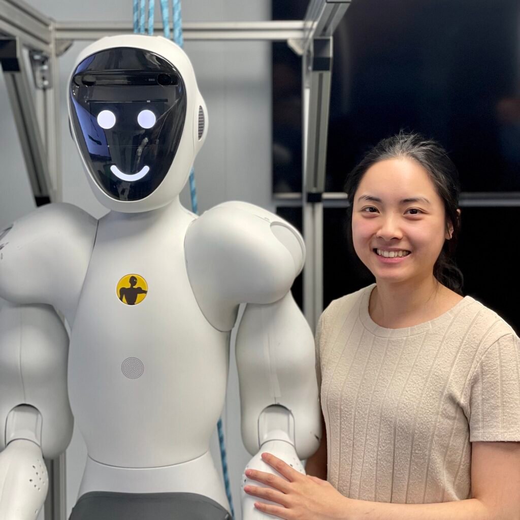 An engineer standing beside a wheeled humanoid robot in an office