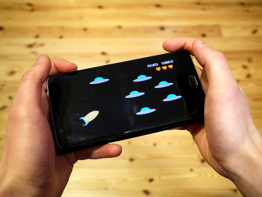 Close-up of hands holding a smartphone while playing a video game