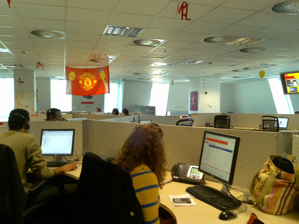 Customer service staff working at desks with headsets in a call centre