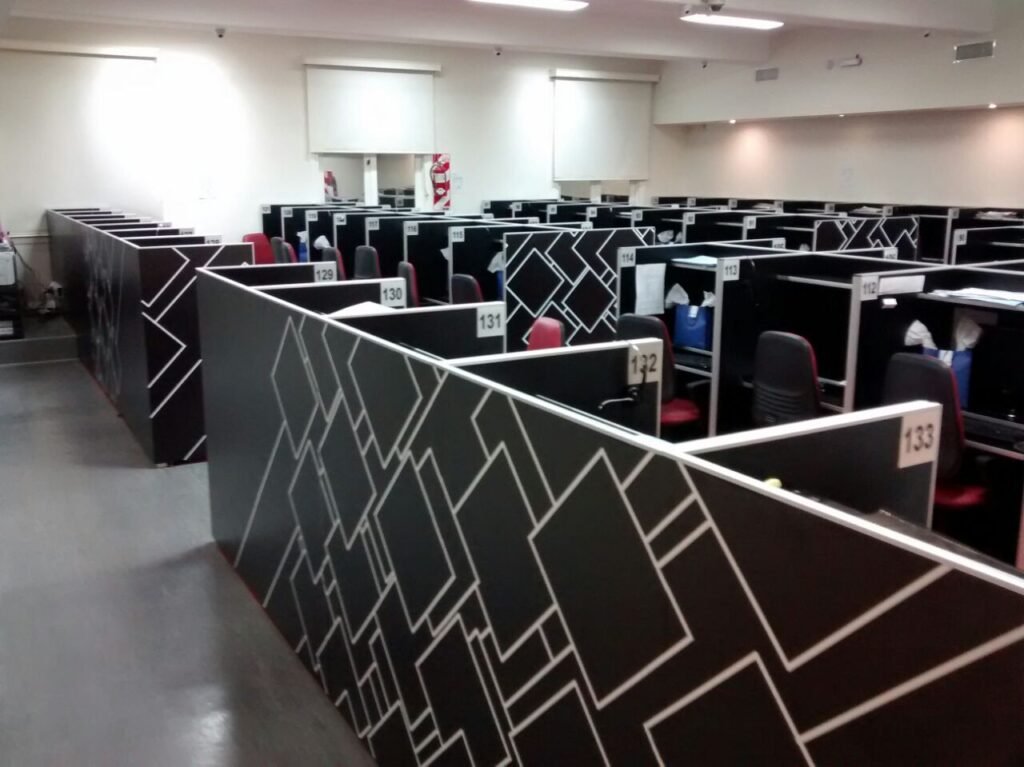 Empty numbered call-centre cubicles with chairs and headsets on the desks