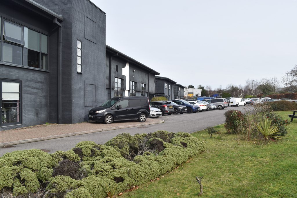 Exterior of a low grey cosmetics factory building with cars parked outside