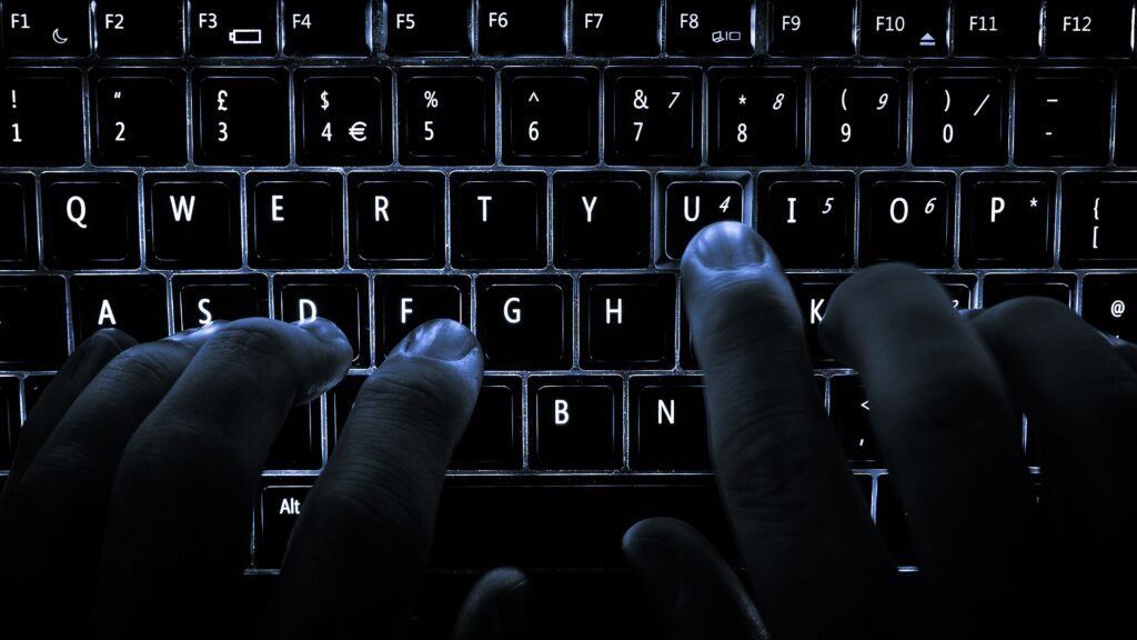 Fingers resting on the home keys of a backlit laptop keyboard