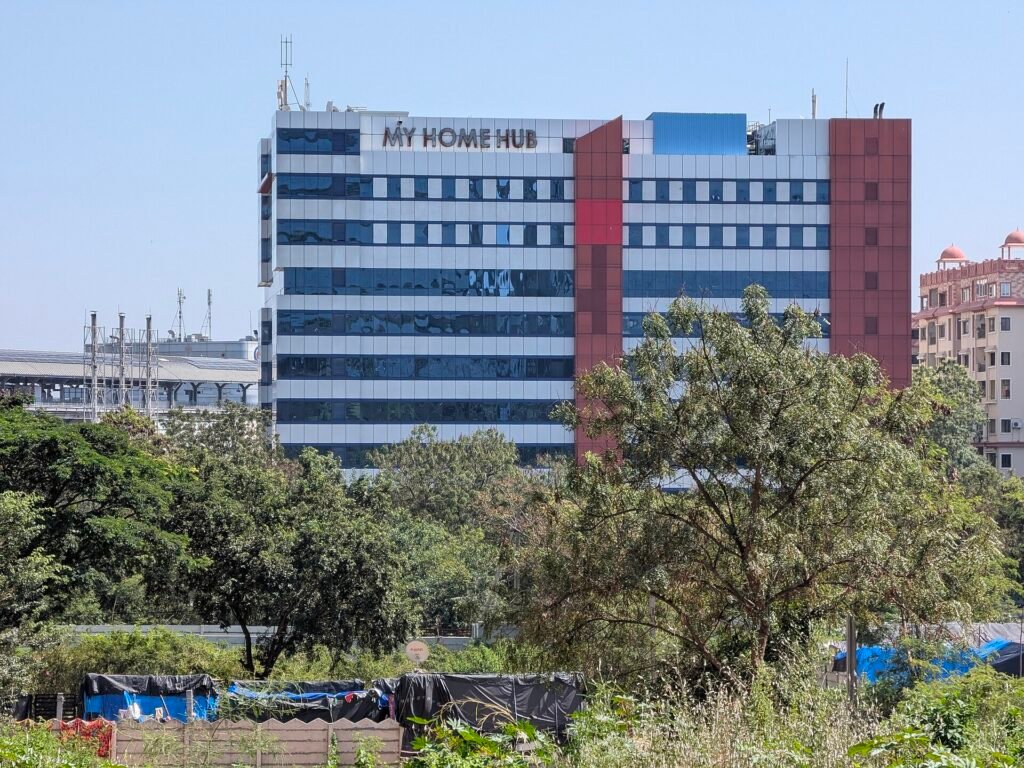 Glass-fronted office building surrounded by trees in Hyderabad’s HITEC City area