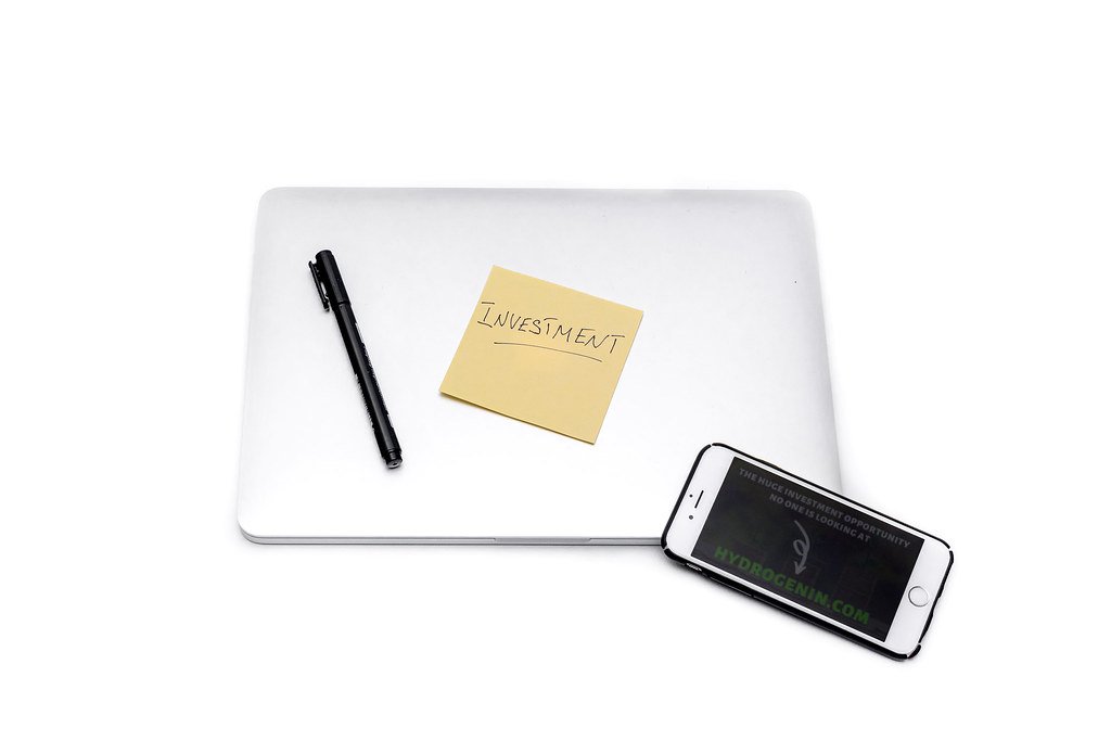 Laptop and smartphone on a desk next to an investment sticker
