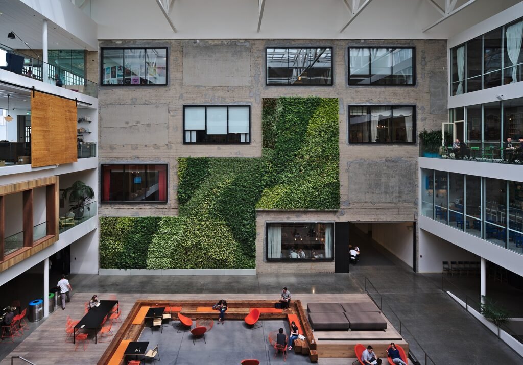 Multi-storey glass-walled atrium inside Airbnb’s San Francisco headquarters with lounge seating on the ground floor