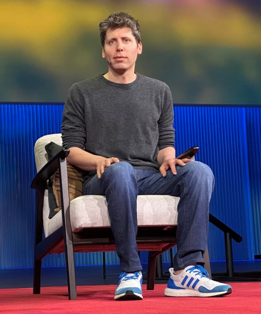 OpenAI CEO Sam Altman speaking on stage at a TED event