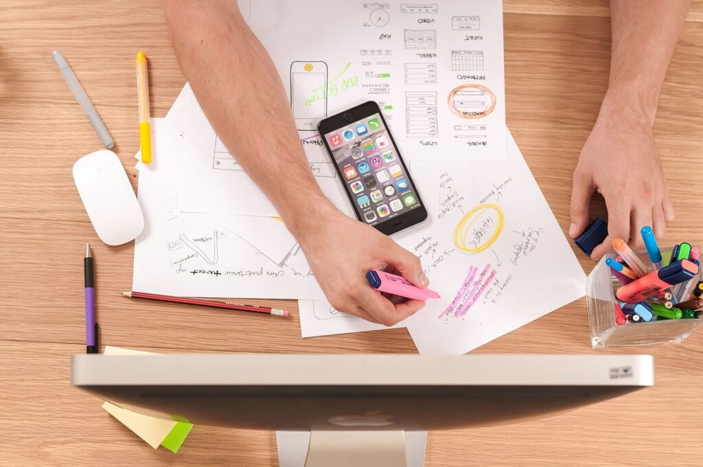 Paper UX prototyping sketches for a mobile app on a desk