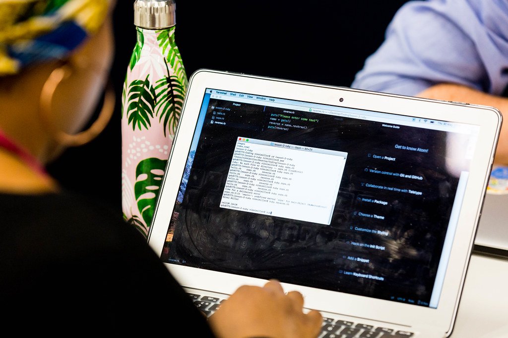 Person typing on a laptop showing a code editor and a terminal window