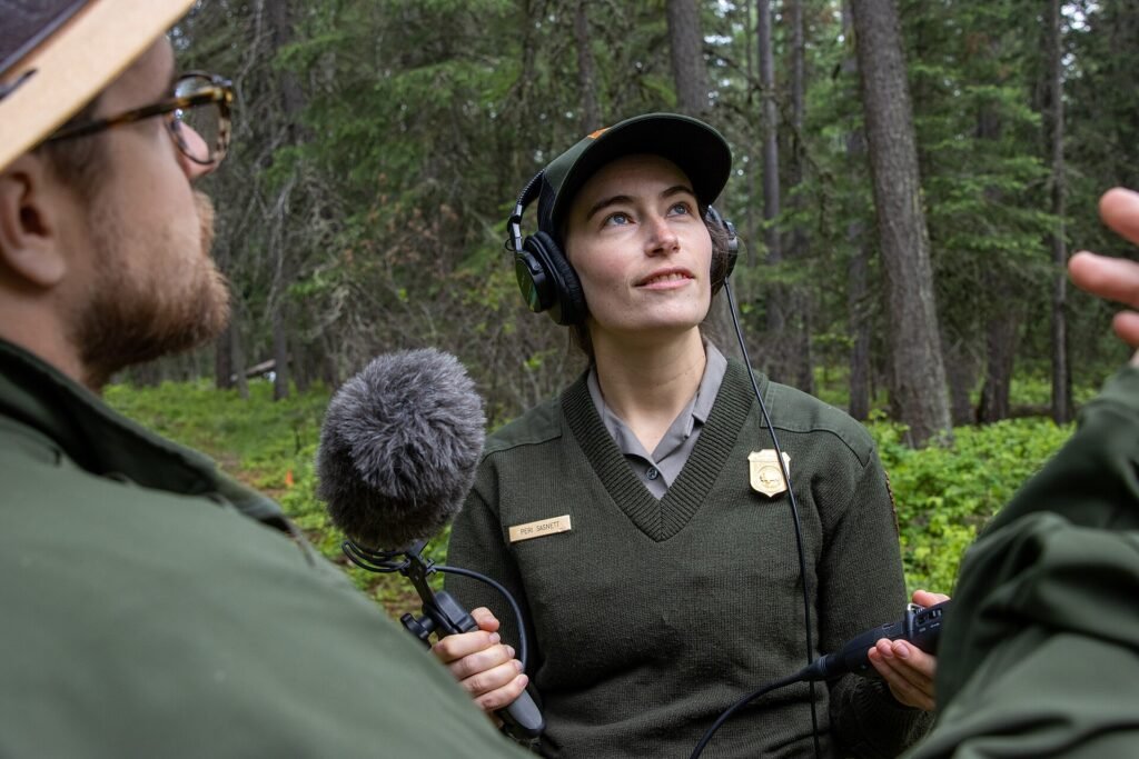 Podcast host holding a microphone and recording equipment in a forest