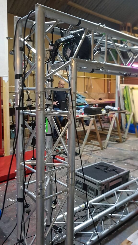 Sections of aluminium box truss stacked in a workshop