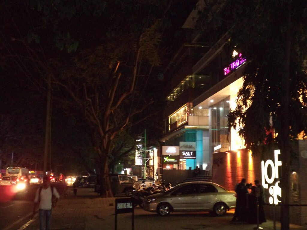 Shops lit up at night on Hundred Feet Road in Indiranagar, Bengaluru
