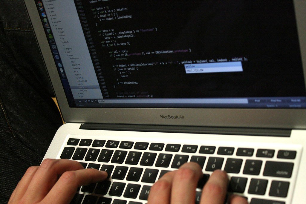 Students working on laptops with code on their screens at a hackathon