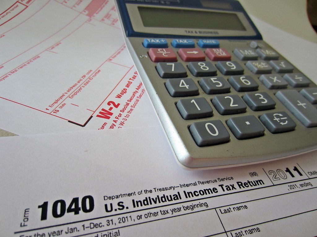 Tax forms on a desk next to a calculator and a pen