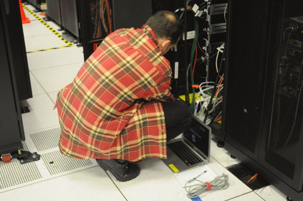 Technician with a laptop working at an open server rack