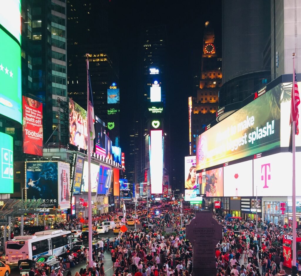 Times Square in New York at night, lit up by large digital advertising billboards